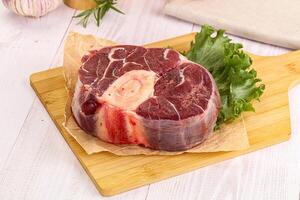A piece of meat on a cutting board with a piece of lettuce photo