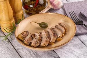 A plate of meat on a wooden table with a knife and fork photo