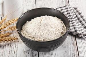 A bowl of flour next to a cup of milk photo