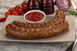 A plate with two sausages and a tomato on it photo