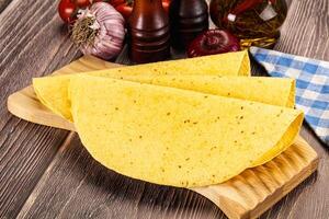 A tortilla on a cutting board with tomatoes and other ingredients photo