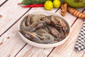 A bowl of shrimp and vegetables on a wooden table photo