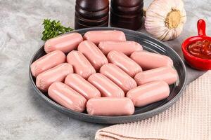 A plate of sausages on a table with garlic and other ingredients photo