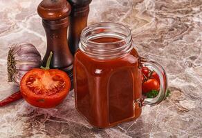 A jar of tomato sauce next to a pepper and a garlic clove photo
