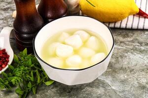 A bowl of lemonade with a lemon and a bottle of vinegar photo