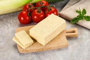 A cutting board with a piece of cheese and tomatoes photo