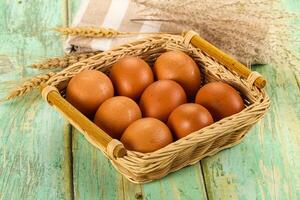 Fresh eggs in basket on wooden table photo