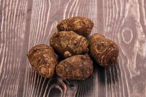 A pile of raw potatoes on a wooden table photo