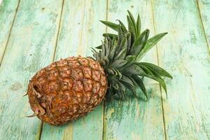 A pineapple is sitting on a wooden table photo