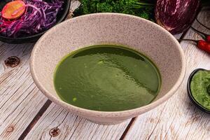 A bowl of green soup next to a bowl of red soup photo