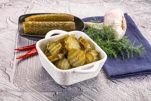 A bowl of pickles and garlic on a table photo