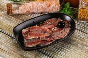 A black dish with meat and spices on a wooden table photo