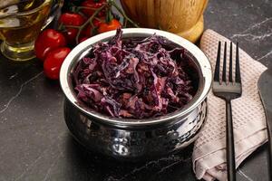 A bowl of red cabbage with a fork and knife photo