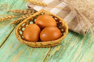 Three eggs in a basket on a wooden table photo
