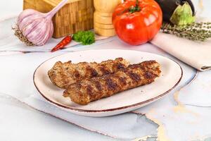 Two meat skewers on a white plate with vegetables photo