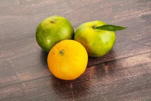 Three oranges and one lemon on a wooden table photo