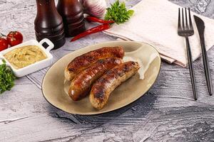 A plate of sausages on a table with a bottle of ketchup and a bottle of photo