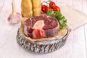 A piece of meat on a wooden table with vegetables photo