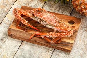 A crab on a cutting board with pineapples and a pineapple photo
