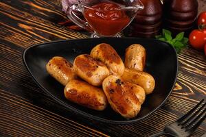 A black plate with some sausages and ketchup photo