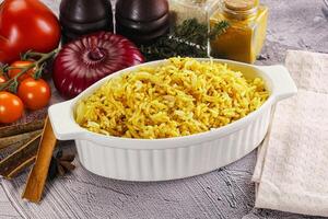 A bowl of rice with spices and vegetables on a table photo