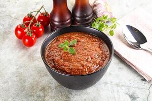 A bowl of tomato sauce with a spoon and a knife photo