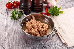 A pan with meat and vegetables on a table photo