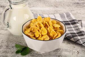 A bowl of corn flakes and a pitcher of milk photo
