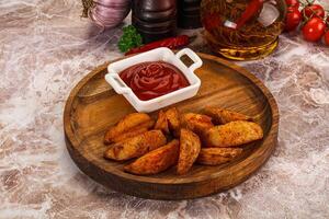 A plate with some potatoes and ketchup on it photo