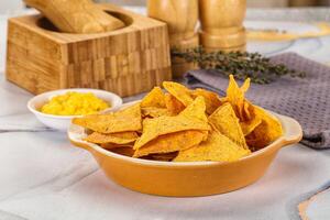 A bowl of chips sitting on a table next to a wooden block photo