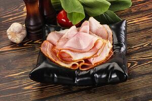 A plate with sliced ham and vegetables on it photo