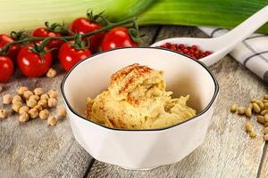 A bowl of hummus with a spoon and some vegetables photo