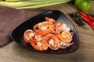 A black bowl with shrimp and other vegetables on a wooden table photo