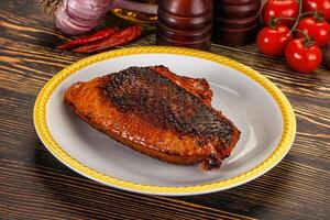 A piece of meat on a plate with tomatoes and other ingredients photo