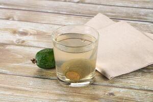 A glass of water with a lime on a wooden table photo