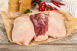 Three raw chicken breasts on a wooden table photo