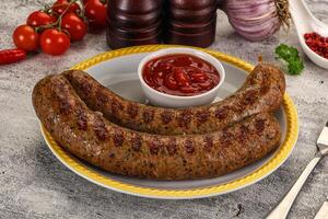 Two sausages on a plate with ketchup and tomatoes photo