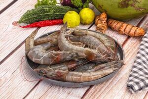 A bowl of shrimp on a table next to vegetables photo