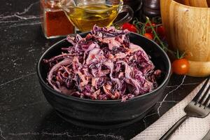 A bowl of red cabbage salad with a fork and knife photo
