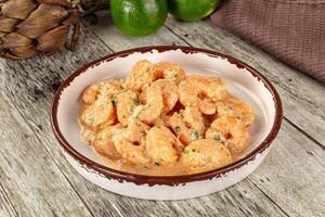 A bowl of shrimp with a side of lime photo