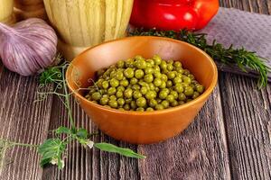 A bowl of peas and garlic on a wooden table photo