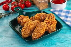 A plate of fried chicken on a table with a bottle of ketchup photo