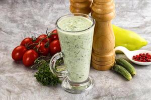 A glass of green smoothie next to a pepper grinder photo