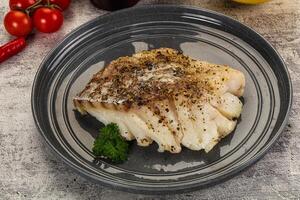 A piece of fish on a plate with some herbs photo
