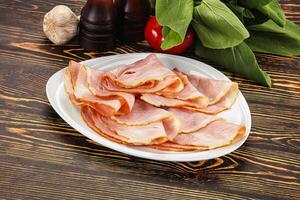 A plate of sliced ham on a wooden table photo