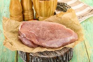 Raw pork on a wooden table with spices and other ingredients photo