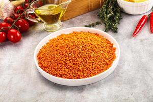 A bowl of red lentils sitting on a counter next to a bowl of tomatoes and garlic photo