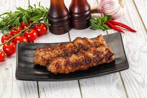 A plate with two meat skewers and a bottle of ketchup photo