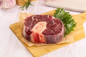 A piece of meat on a cutting board with a leaf of lettuce photo