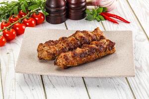 Two meat skewers on a plate with tomatoes and spices photo